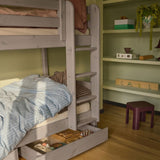 FLEXA brown underbed drawers from CLASSIC range with blue striped bedding, shelves, child-safe design in a kid’s room.