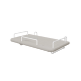 FLEXA bedside tray from the GREY collection, grey MDF with four white metal handles, child-safe edges, by a bed.