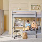 FLEXA grey High Bed with sofa, ladder and safety rail in a bright room with bookshelves, plants and wall art.